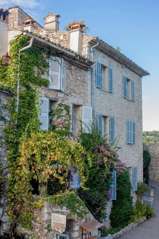 Gîte de charme avec volets bleus et façade fleurie.